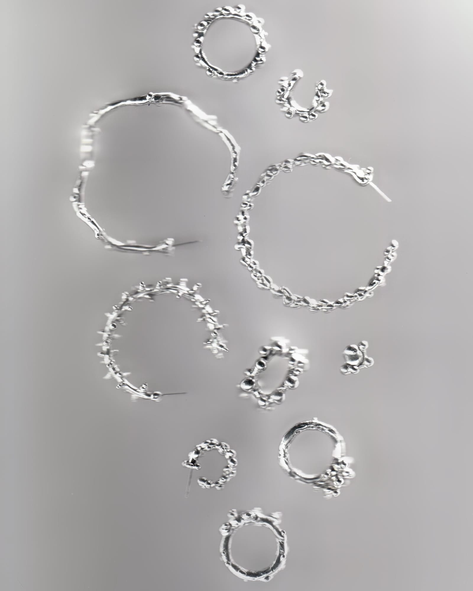 beaded silver hoops and rings laid out on a grey surface