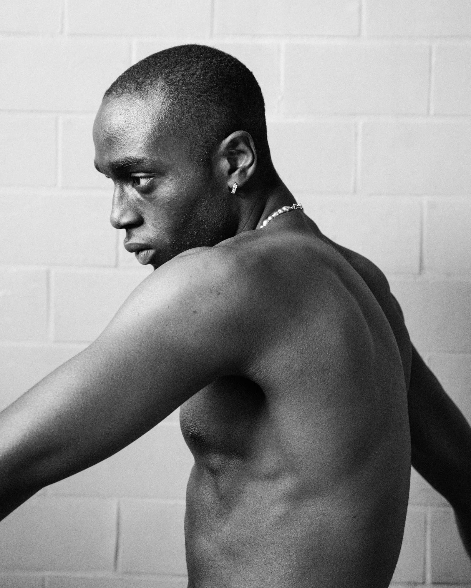 black and white portrait of a shirtless man wearing a silver chain and earring