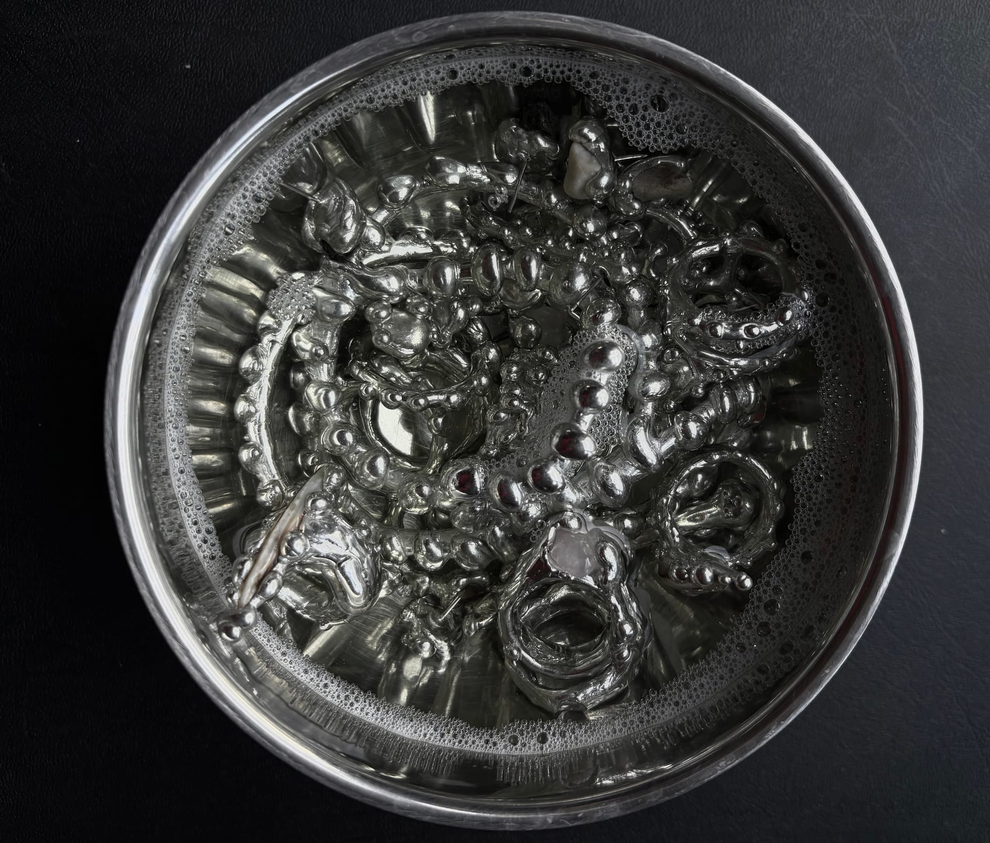 a metal bowl filled to the brim with silver pieces